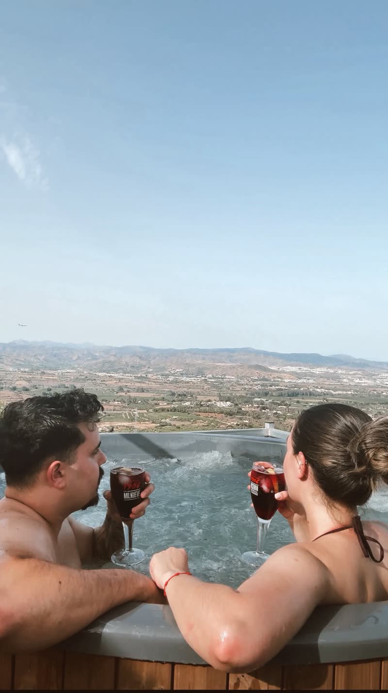 Pareja brindando en el Infinity Jacuzzi de Sunview Park con vistas al valle de Málaga