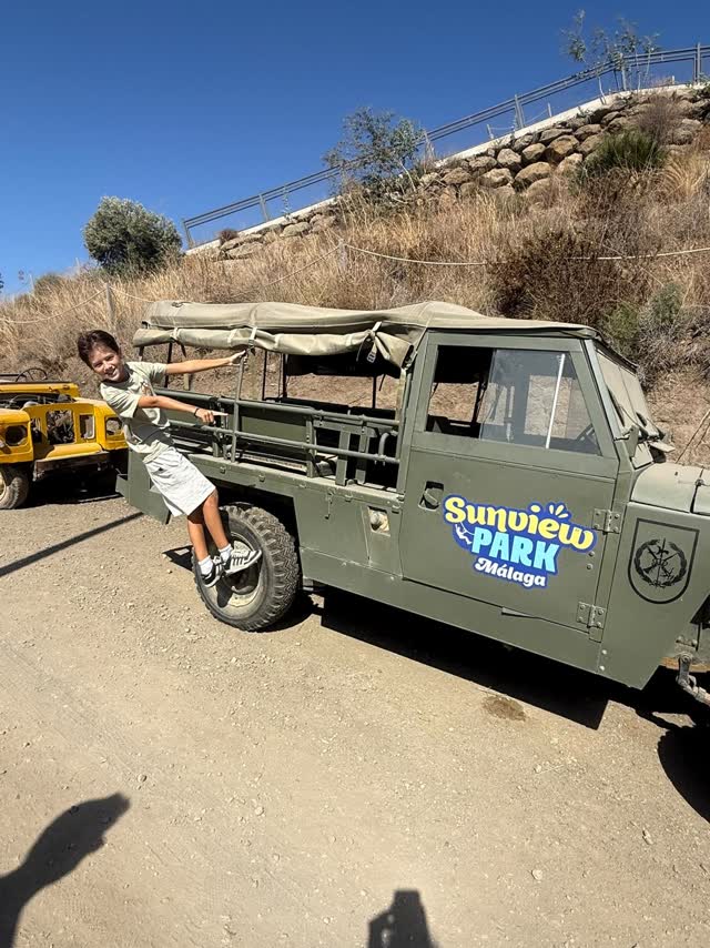 Un niño posando junto al Land Rover del parque